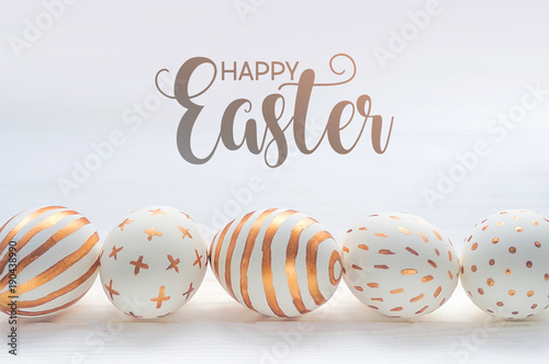 Happy easter postcard banner. Golden Easter eggs on wooden white vintage background.