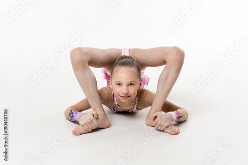 A young teenage girl in leotard shows gymnastic and ballet exercises on a white background. photo