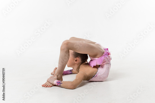 A young teenage girl in leotard shows gymnastic and ballet exercises on a white background. photo