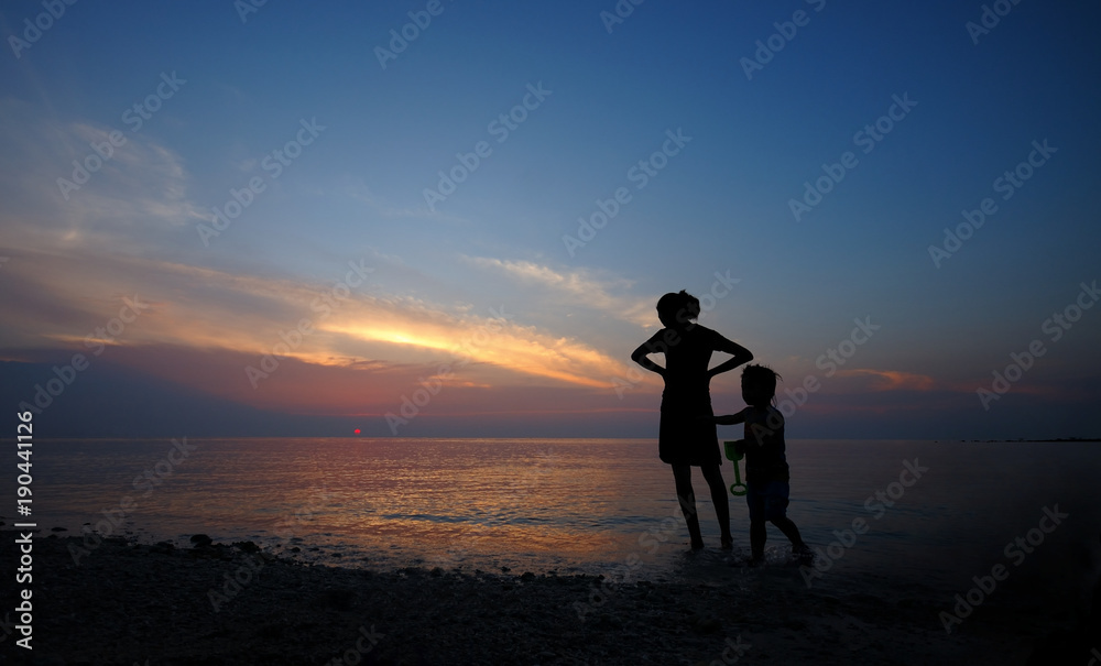 Mother and child in sunset at the beach.