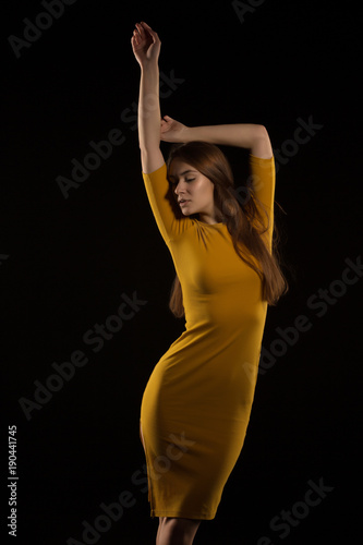 Sensual brunette woman with long hair posing in yellow dress at studio