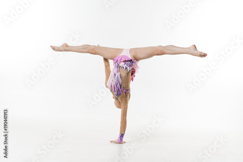 A young teenage girl in leotard shows gymnastic and ballet exercises on a white background. photo