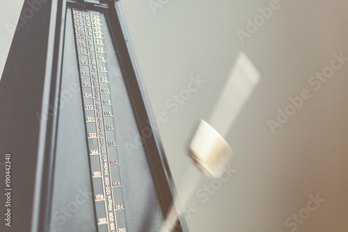 Color shot of a vintage metronome, on gray background.