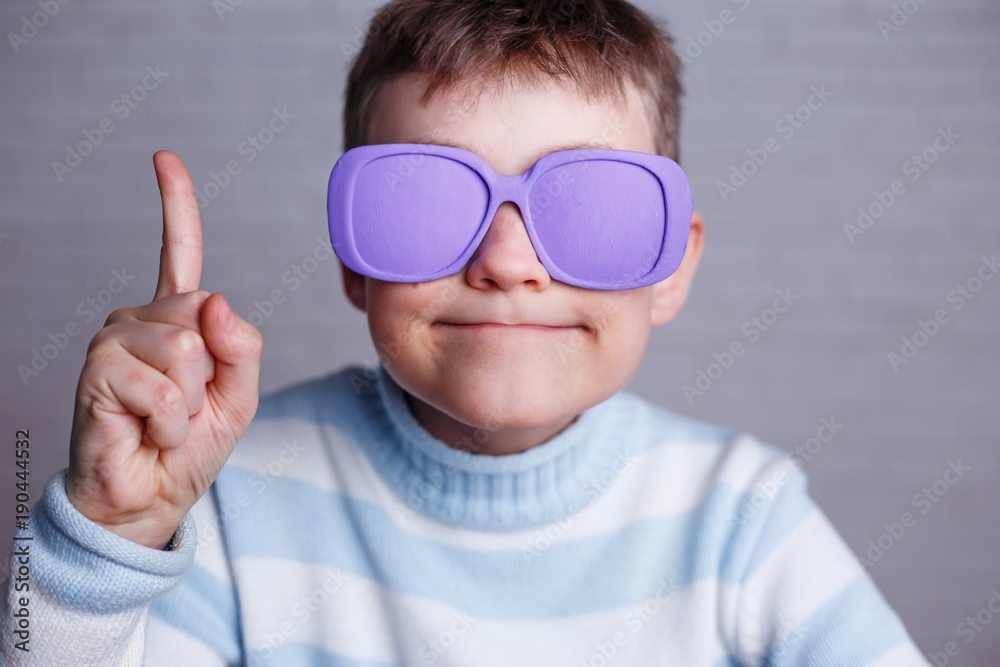 Cute boy in violet sunglasses with opaque lenses pointing upwards Cute boy in violet sunglasses with opaque lenses pointing upwards