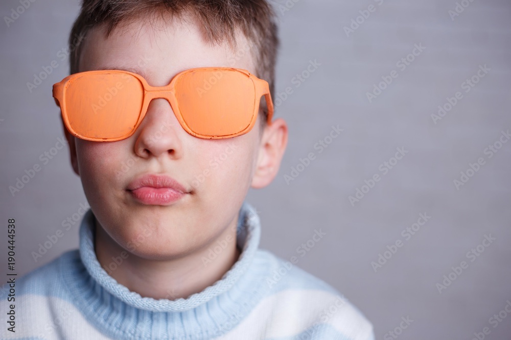 Close up portrait of cute boy in orange sunglasses with opaque lenses Close up portrait of cute boy in orange sunglasses with opaque lenses