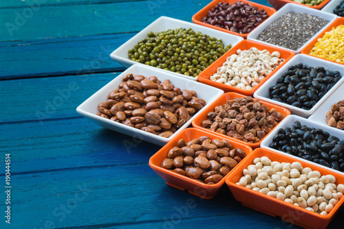 Different dry legumes in containeron blue plank, Multicolor dried beans for eating healthy