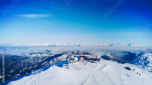 Aerial view of skiers at ski resort in the winter mountain peak with reastaurant in Slovakia, Jasna Nizke Tatry. View from above photo