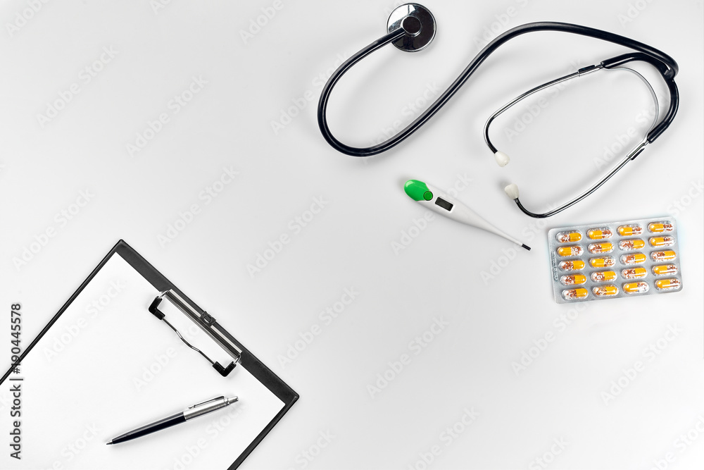 Stethoscope in the office of doctors.Top view of doctor's desk table, blank paper on clipboard with pen. Copy space. Designer's blank Stethoscope in the office of doctors.Top view of doctor's desk table, blank paper on clipboard with pen. Copy space. Designer's blank