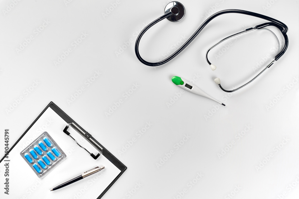 Stethoscope in the office of doctors.Top view of doctor's desk table, blank paper on clipboard with pen. Copy space. Designer's blank