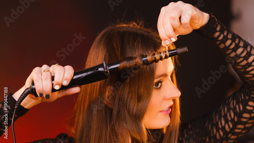 Happy woman curling her long brown hair