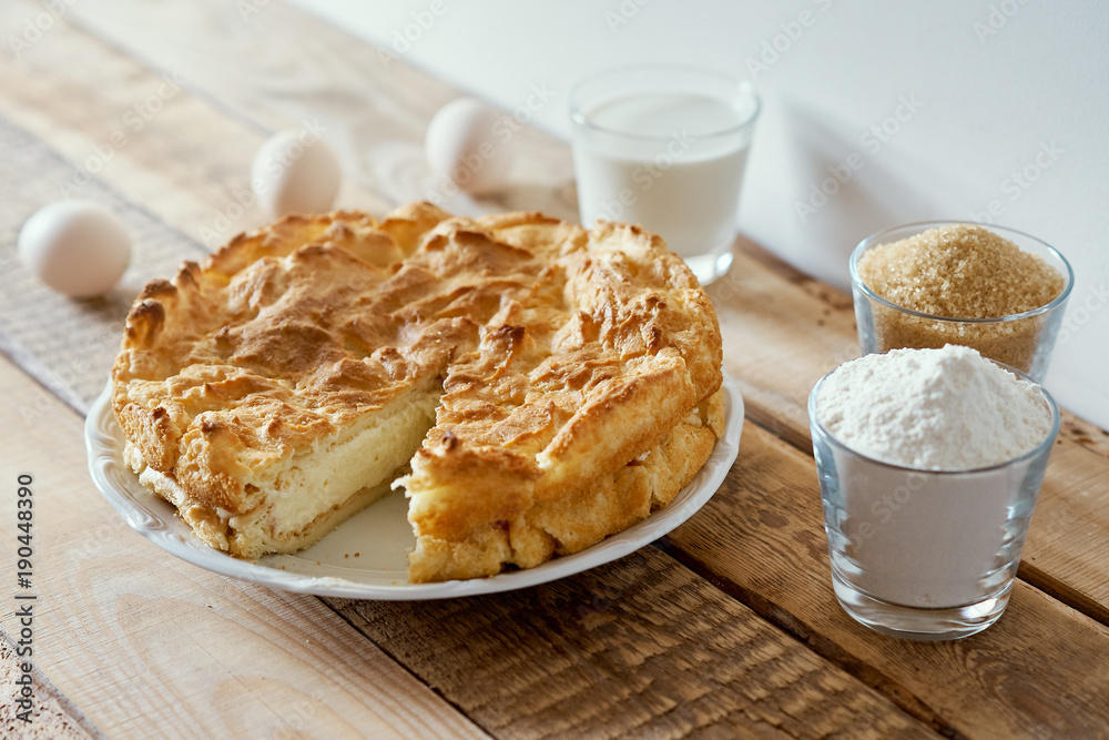 delicious cake, eggs, flour, milk and sugar placed on an old wooden table delicious cake, eggs, flour, milk and sugar placed on an old wooden table