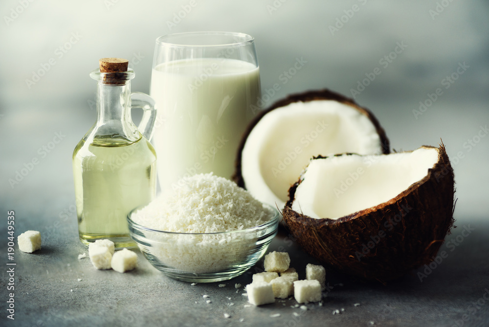 Coconuts products - milk, oil, shavings on grey concrete background. Copy space. Hair, skin and body treatment. Coconuts products - milk, oil, shavings on grey concrete background. Copy space. Hair, skin and body treatment.