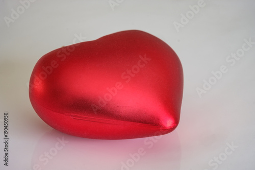 фотографія Single satin red heart sitting on a white background