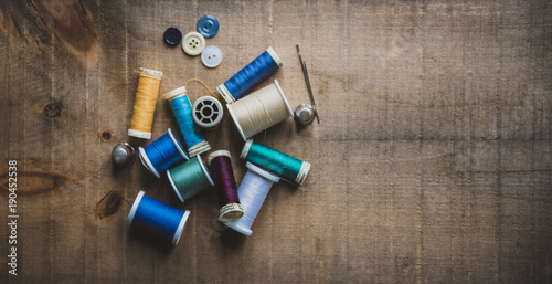 High angle view of colorful spools with thimbles and buttons on wooden table at workshop photo