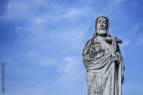 Jesus Christ ancient statue against the background of a blue sky