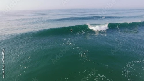 Drone shot of man surfing on huge waves in sea during summer vacation photo