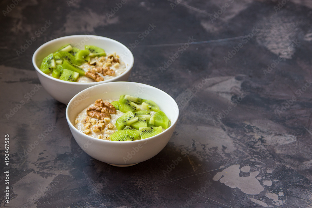 Oatmeal with kiwi fruit and walnuts. Two bowls porridge