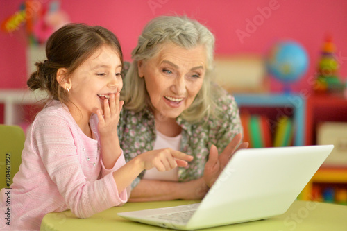  girl with grandmother using laptop