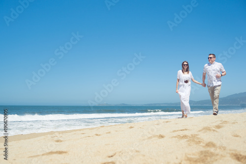 Young romantic couple walking on the beach © Nuli_k