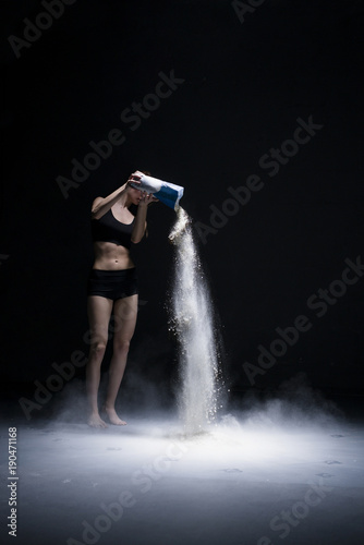 Slim girl pouring flour from packet on the floor