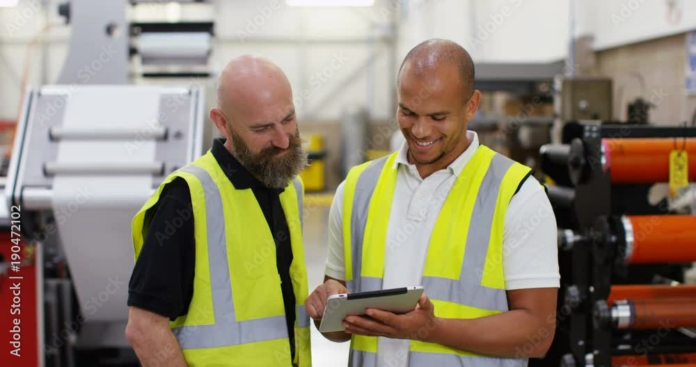 4k, Two male colleagues with digital tablet discussing something inside a printing factory. Slow motion. 4k, Two male colleagues with digital tablet discussing something inside a printing factory. Slow motion.