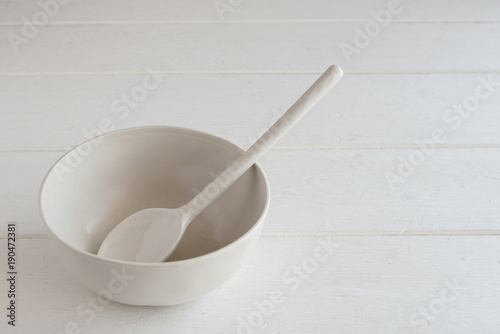 white bowl and spoon ceramic on a white wooden background