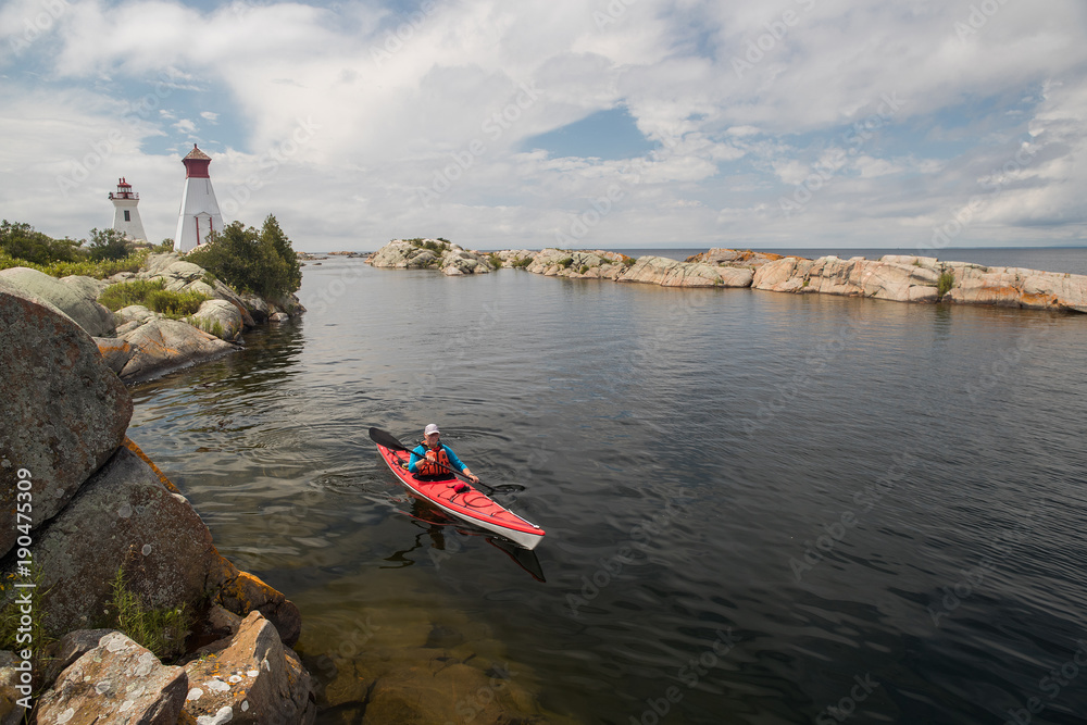 Active senior paddling a sea kayak on Georgian Bay, Ontario, Canada.