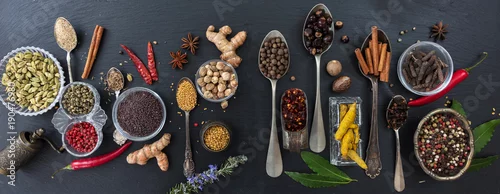 Obraz  z motywem Variety of colorful spices and herbs on black stone background, top view, banner