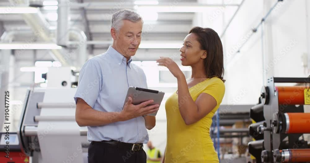 4k, Two managers standing inside a printing and packaging plant with a digital touchscreen tablet. Slow motion. 4k, Two managers standing inside a printing and packaging plant with a digital touchscreen tablet. Slow motion.