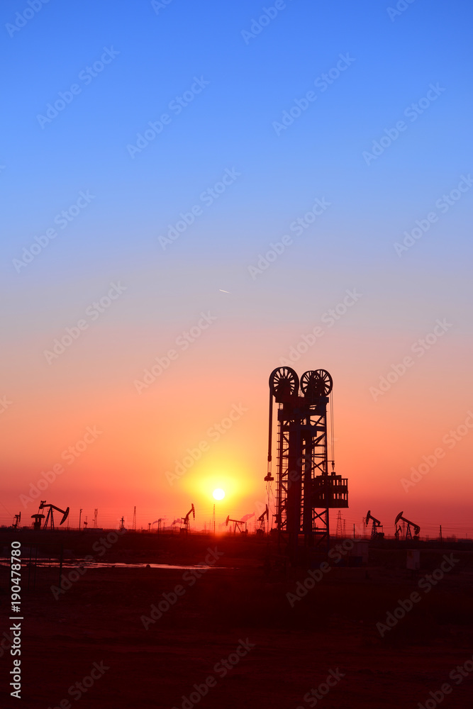 Working oil derrick in field under the setting sun Working oil derrick in field under the setting sun