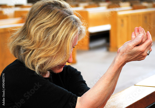 Mature female beauty praying in church.