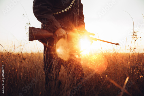Hunter holds gun at sunrise photo