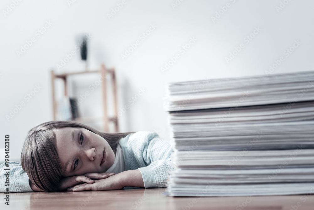 Sad moment. Poor schoolgirl resting her head on a table and dreaming while focusing her attention on an enormously big pile of business documents. Sad moment. Poor schoolgirl resting her head on a table and dreaming while focusing her attention on an enormously big pile of business documents.