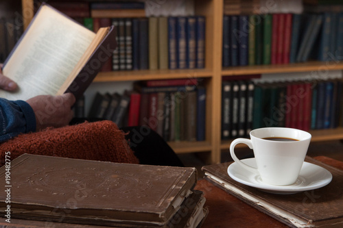 Sweet moments of relaxation with books and a cup of coffee. Vintage books, glasses, chair, library, man
