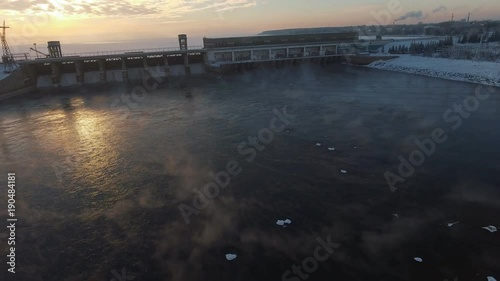 Wallpaper Mural Fly over soaring ice water and approaching the building of a power station. Novosibirsk reservoir and hydroelectric power station: frozen water and sun, reflected in the ice crust. Aerial view. Torontodigital.ca