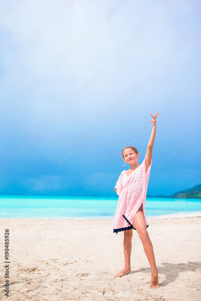 Beautiful little girl in dress at beach having fun. Funny girl enjoy summer vacation.