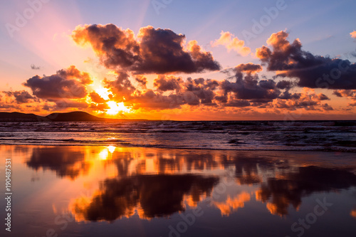 Sun and clouds reflecting in the sea water of Famara beach, Lanzarote, Canary Islands, Spain at the sunset