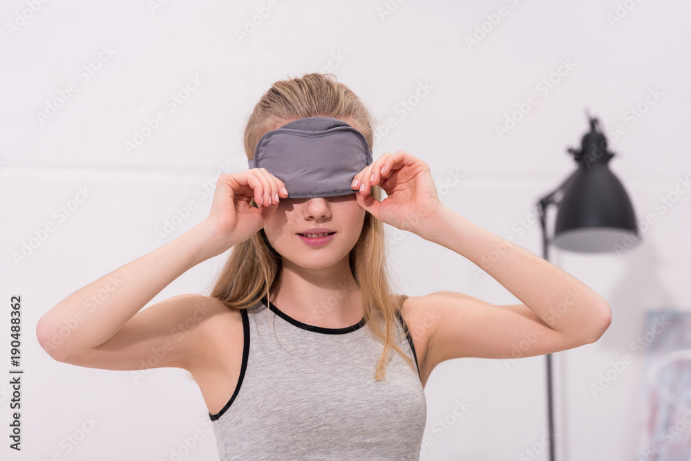 beautiful young woman putting on sleep mask beautiful young woman putting on sleep mask