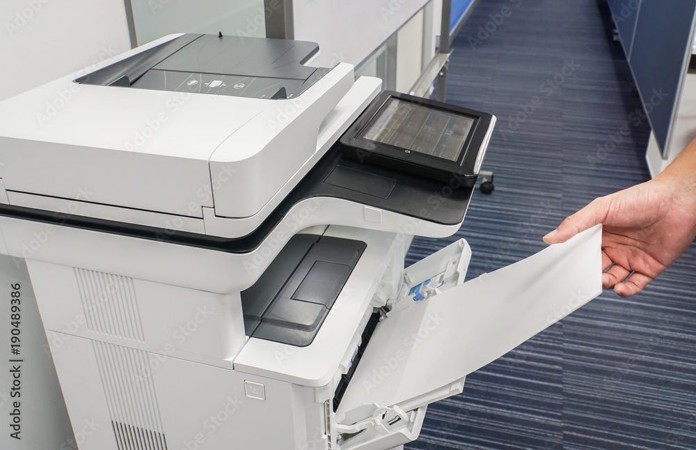 close up businessman hand put blank paper sheet into printer input for copying and scanning documents
