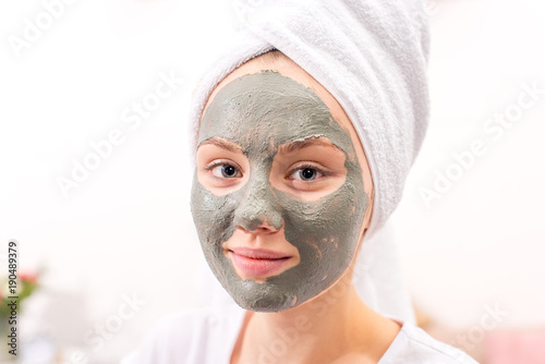 beautiful young woman with cosmetic clay mask at home