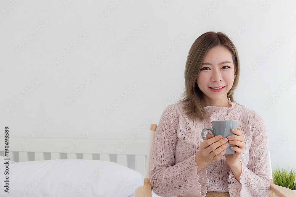 Beauty Asian woman smile and holding coffee cup on her bed in the morning,Copy space Beauty Asian woman smile and holding coffee cup on her bed in the morning,Copy space