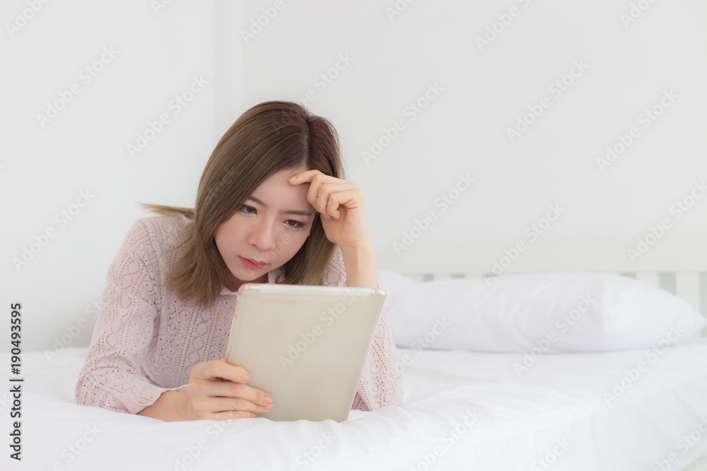 Asian woman looking in tablet on bed Asian woman looking in tablet on bed