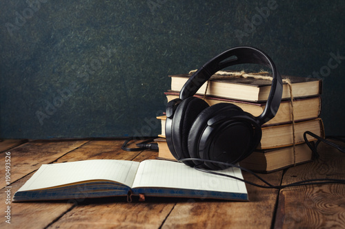 Books stand with a pile, Headphones, outdoor Diary on a wooden background. The Concept of Audio Books and Audio Education photo