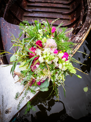 the bridal bouquet is on the wooden boat at the wedding shoot, a great idea
