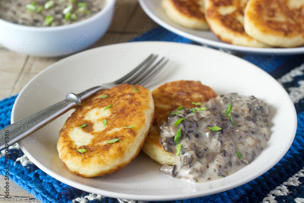 Potato cutlets or pancakes with mushroom sauce and green onions. Rustic style.