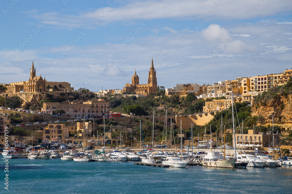Bay view of Mgarr, town and harbour where ferries dock at the east end of island Gozo, Malta. Popular touristic route, attraction and destination.