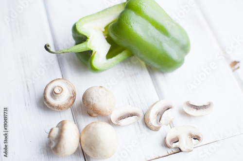 Healthy Food, Vegetarian Concept. A sweet green pepper cut in halves and champignones on a white wooden background with copy space, top view photo