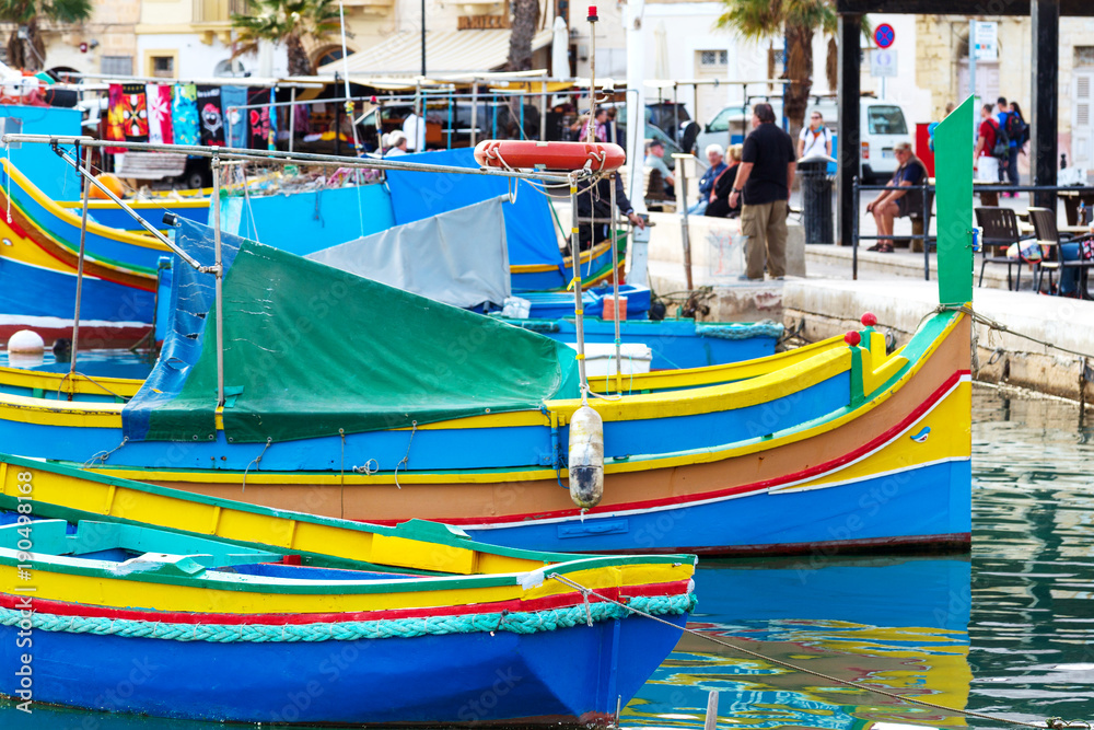 Traditional colourful painted Maltese fishing boats, called luzzu, in the small fishing village Marsaxlokk on Malta. Traditional colourful painted Maltese fishing boats, called luzzu, in the small fishing village Marsaxlokk on Malta.