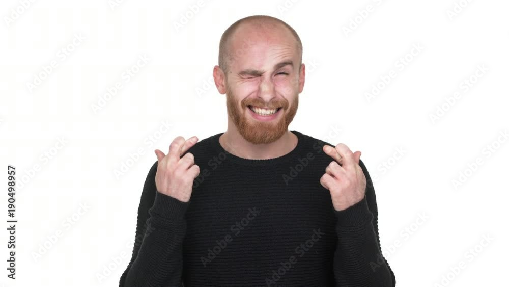 Portrait of hopeful young man wishing good luck keeping fingers crossed begging god please with smile, over white background. Concept of emotions Portrait of hopeful young man wishing good luck keeping fingers crossed begging god please with smile, over white background. Concept of emotions