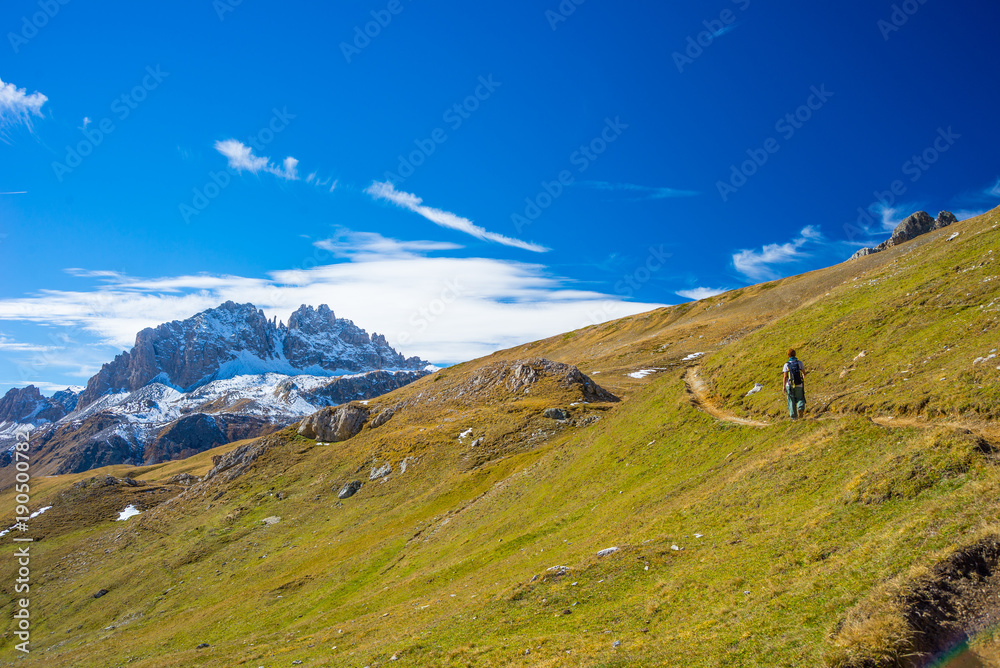 Hiker walking on a colorful valley with great panoramic view and vivid colors. Wide angle shot in the Italian French Alps.